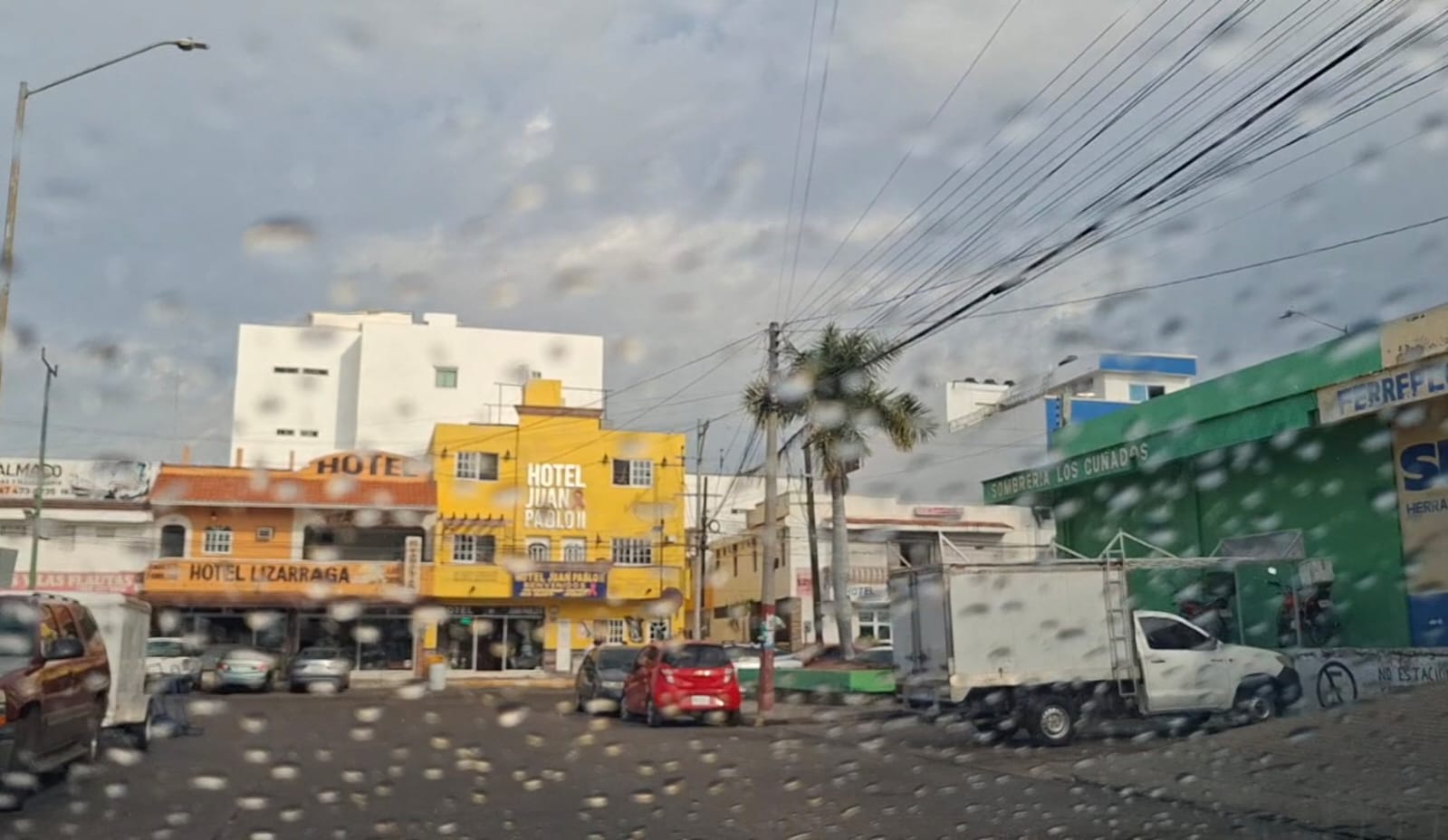 Perspectiva de la calle desde dentro de un auto, donde se ve el vidrio mojado por lluvias