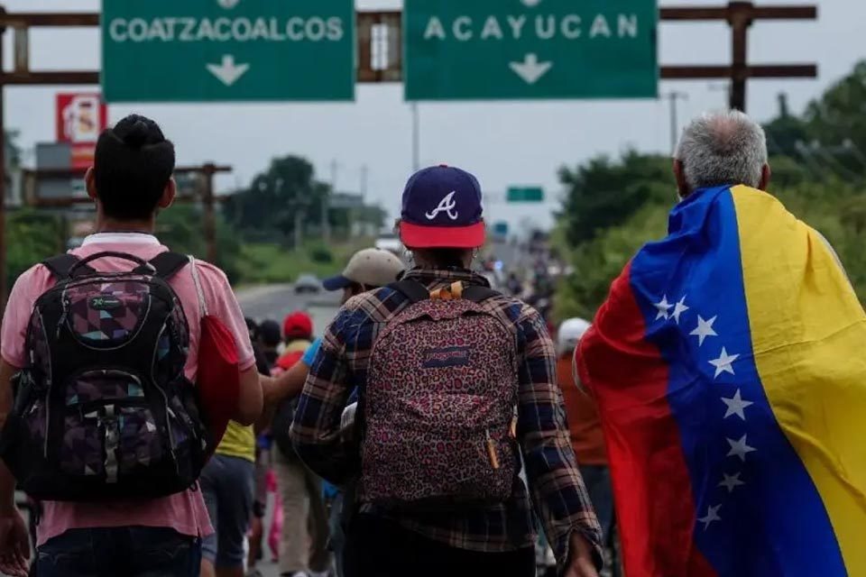 PErsonas de espald con mochilas y una de ellas con una bandera