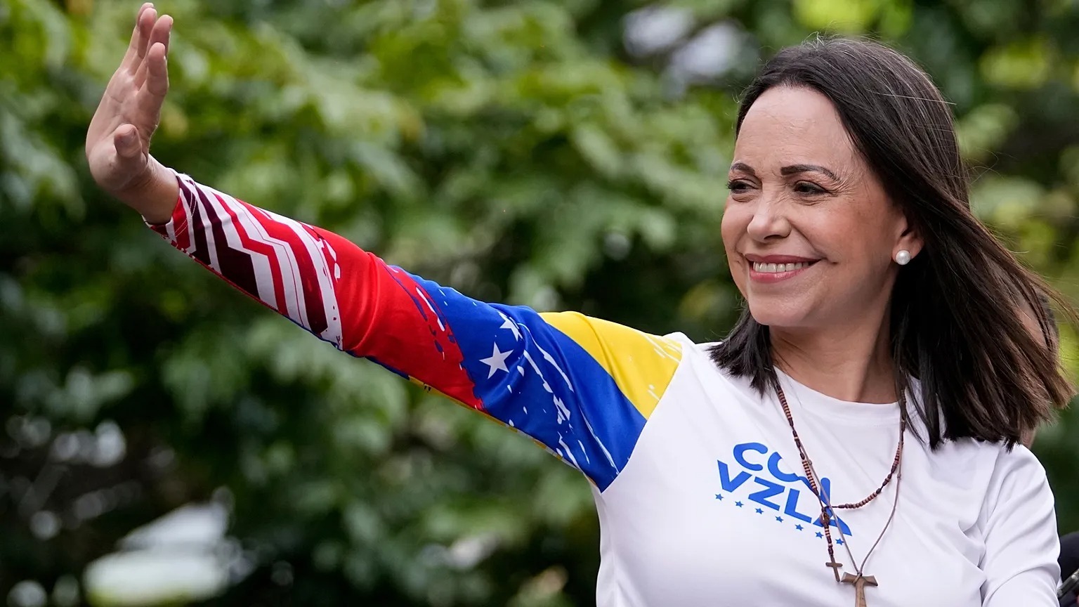 Mujer viendo hacia un lado sonriendo mientras levanta su brazo y saluda