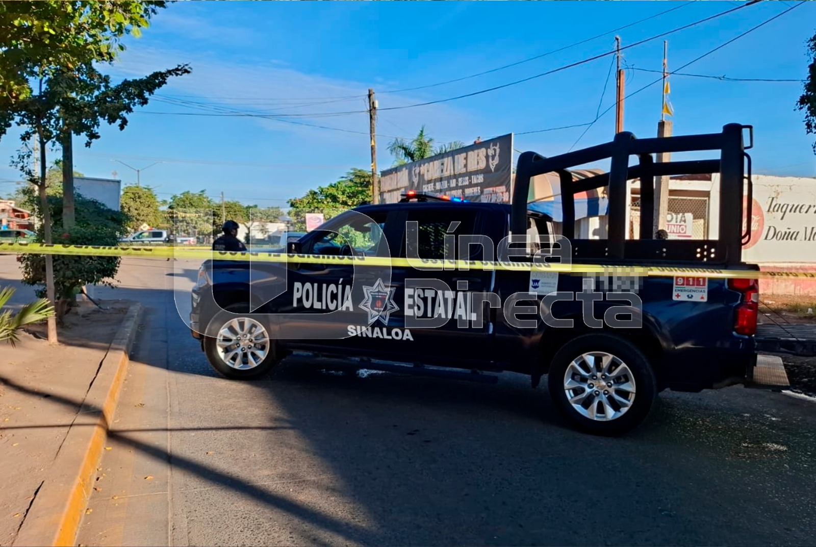 Unidad policiaca atravesada en una calle donde hay una cinta amarilla de precaución