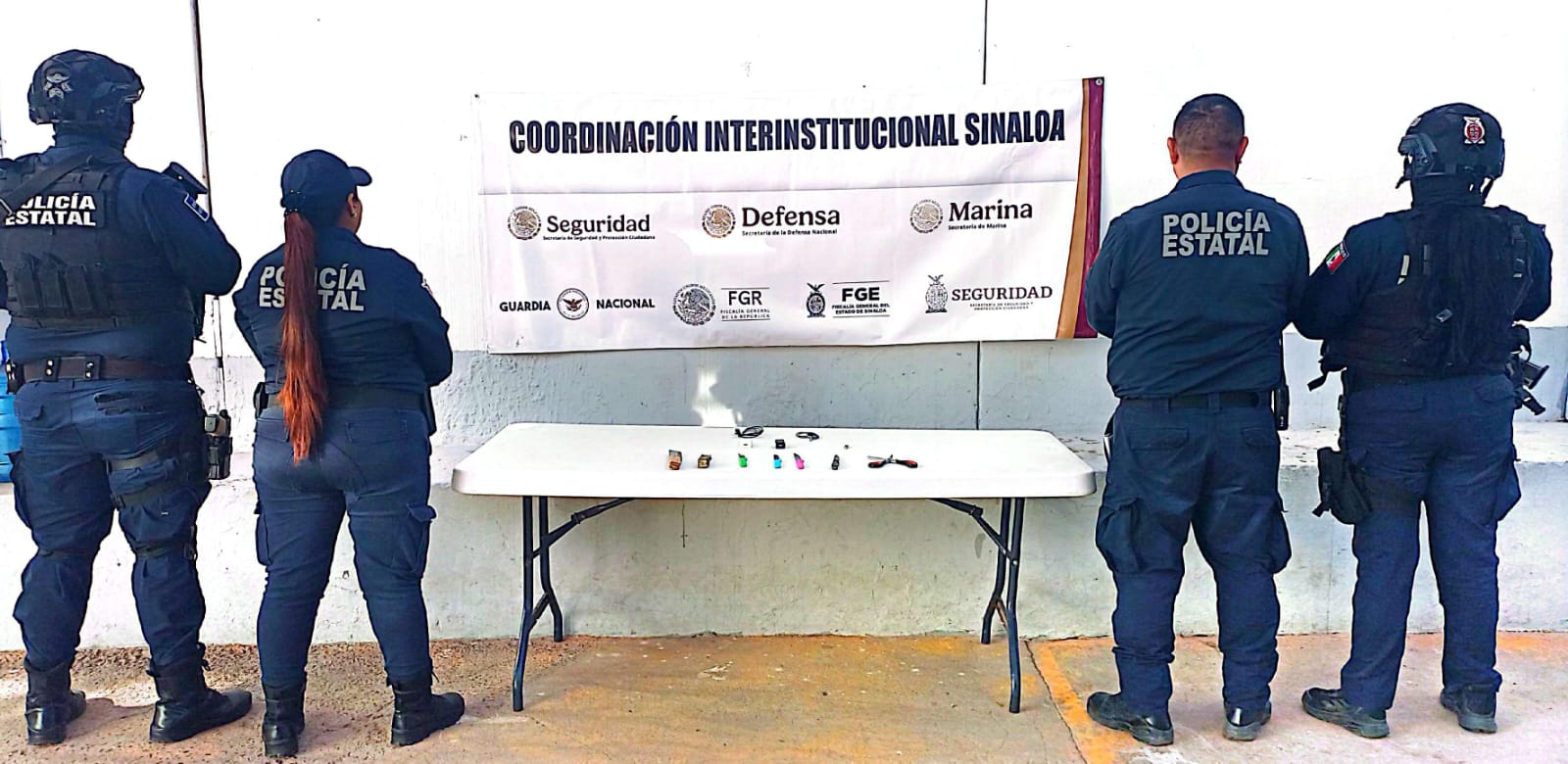 Cuatro policías municipales junto a aseguramiento en una mesa