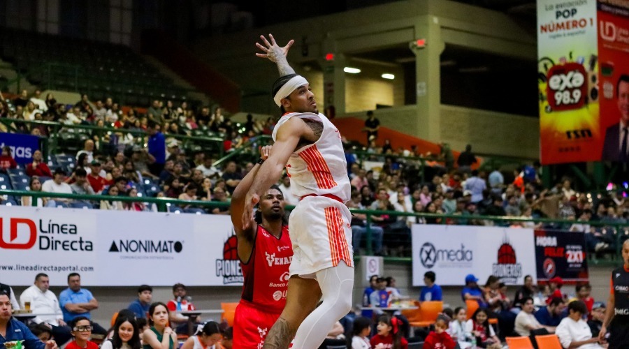 Jugador de baloncesto saltando durante un partido en un gisnasio con personas alrededor