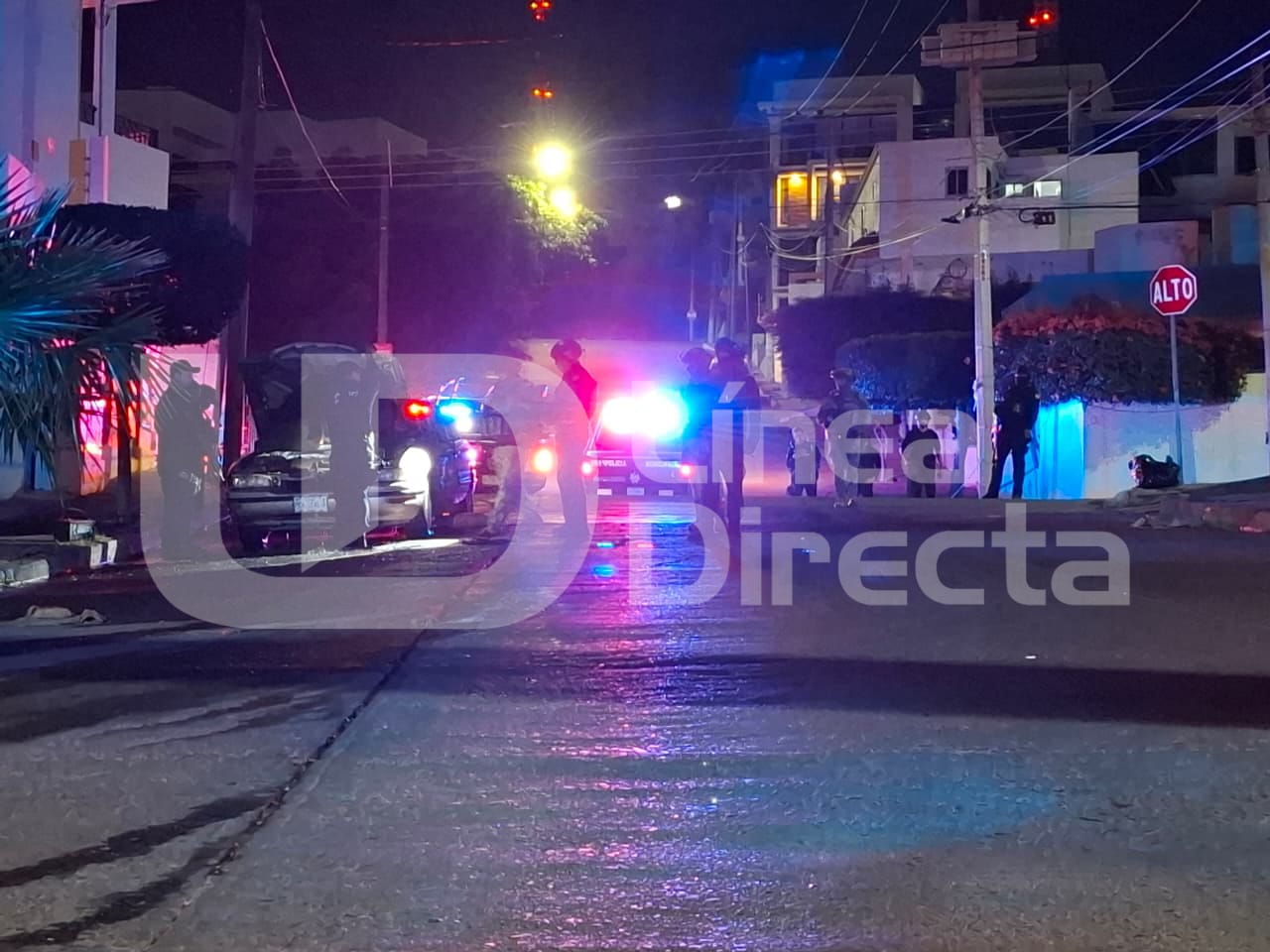 Luces de una patrulla y elementos policiacos desplegados en una calle