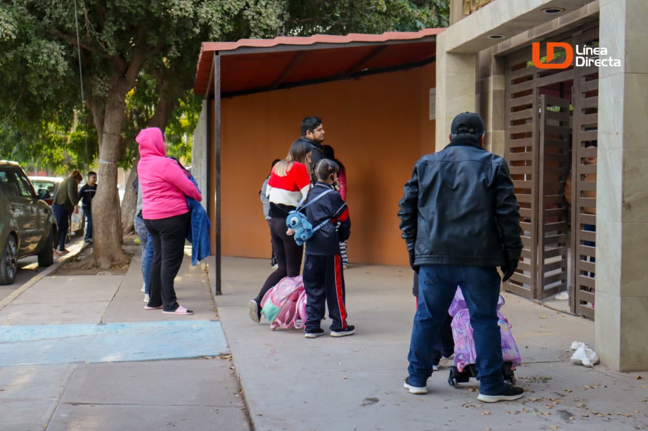 Estudiantes y padres de familia en la entrada de la escuela