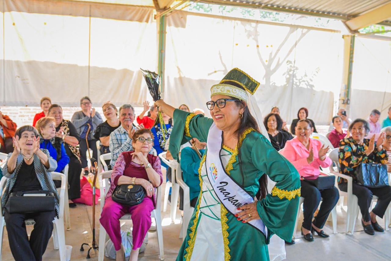 Mujer con atuendo especial y corona levantando un objeto frente a personas sentadas
