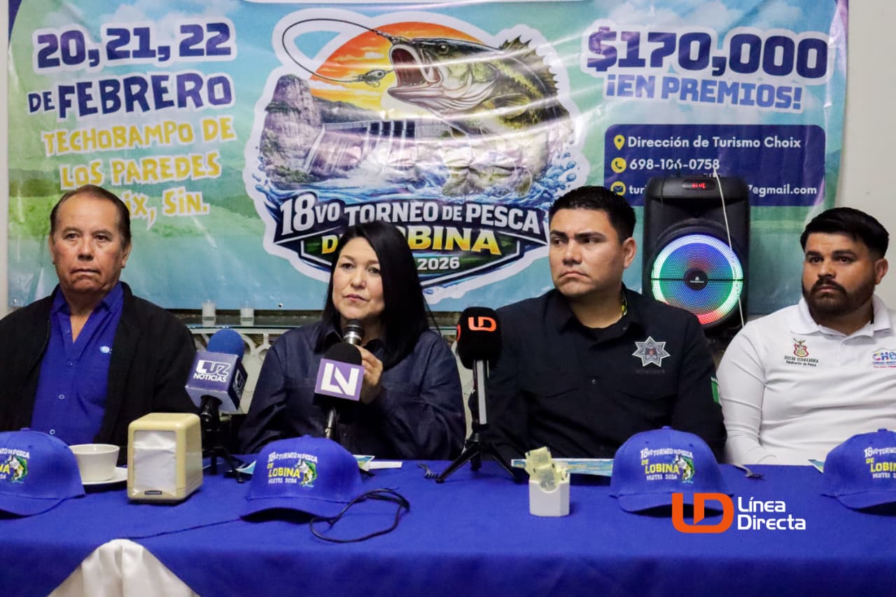 Personas en una rueda de prensa y al fondo una lona