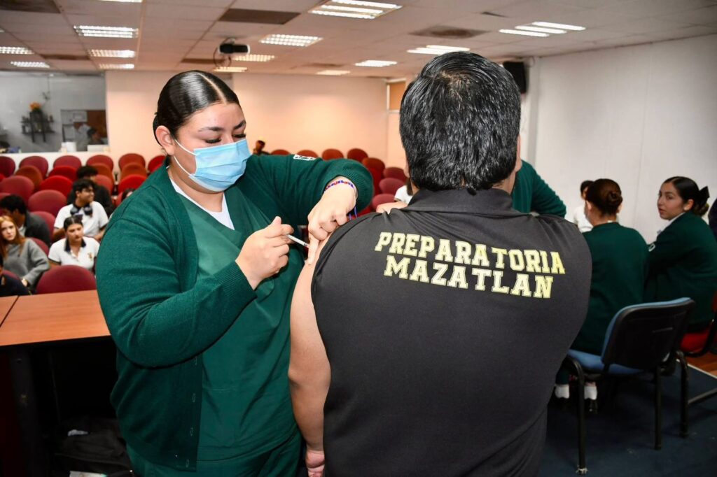 Estudiante siendo vacunado por personal de salud.