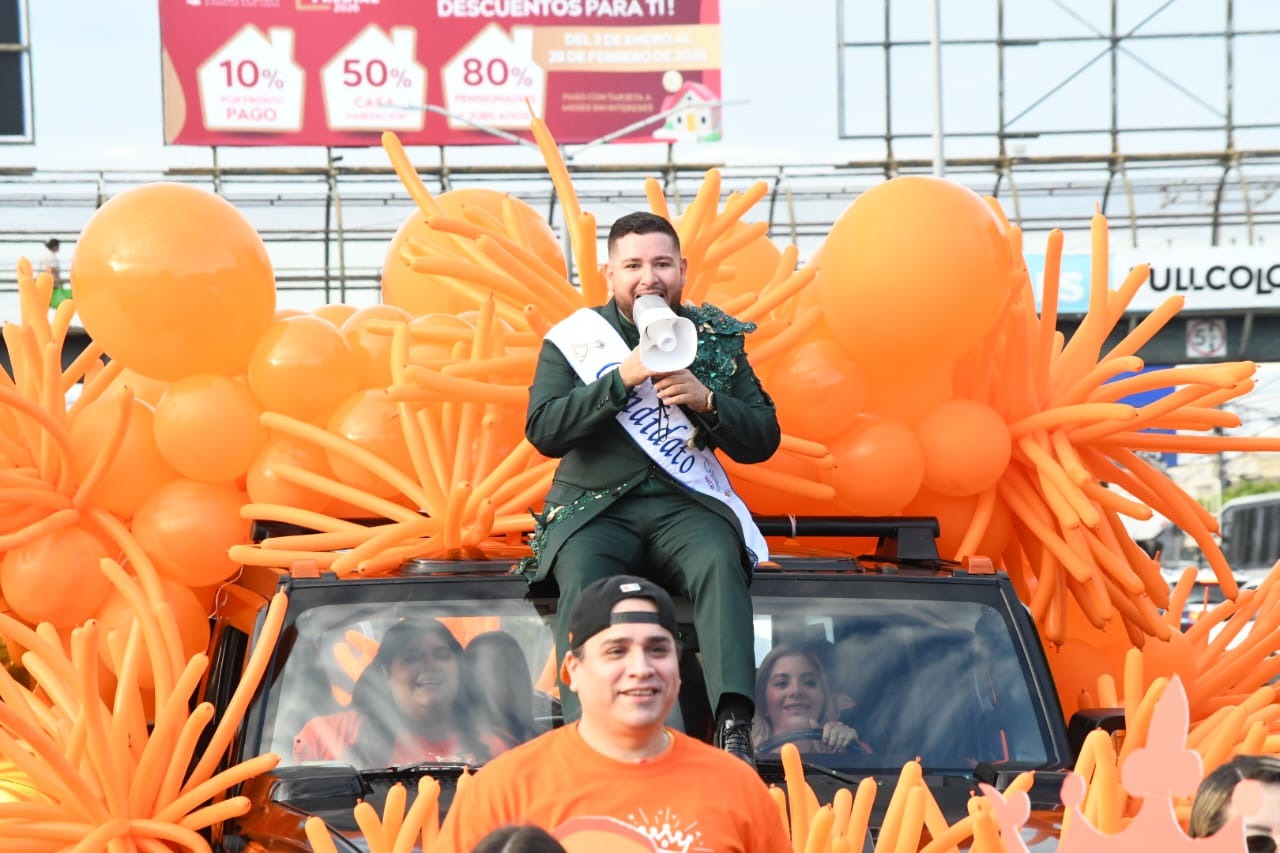 Víctor Joel, candidato a Rey de la Alegría del Carnaval de Mazatlán, sobre una camioneta con adornos y globos color naranja