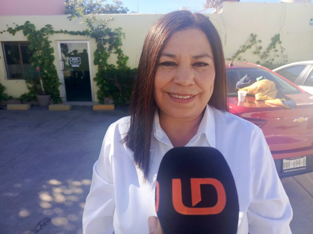 Mujer viendo hacia le frente sonriendo con un micrófono negro con letras naranjas