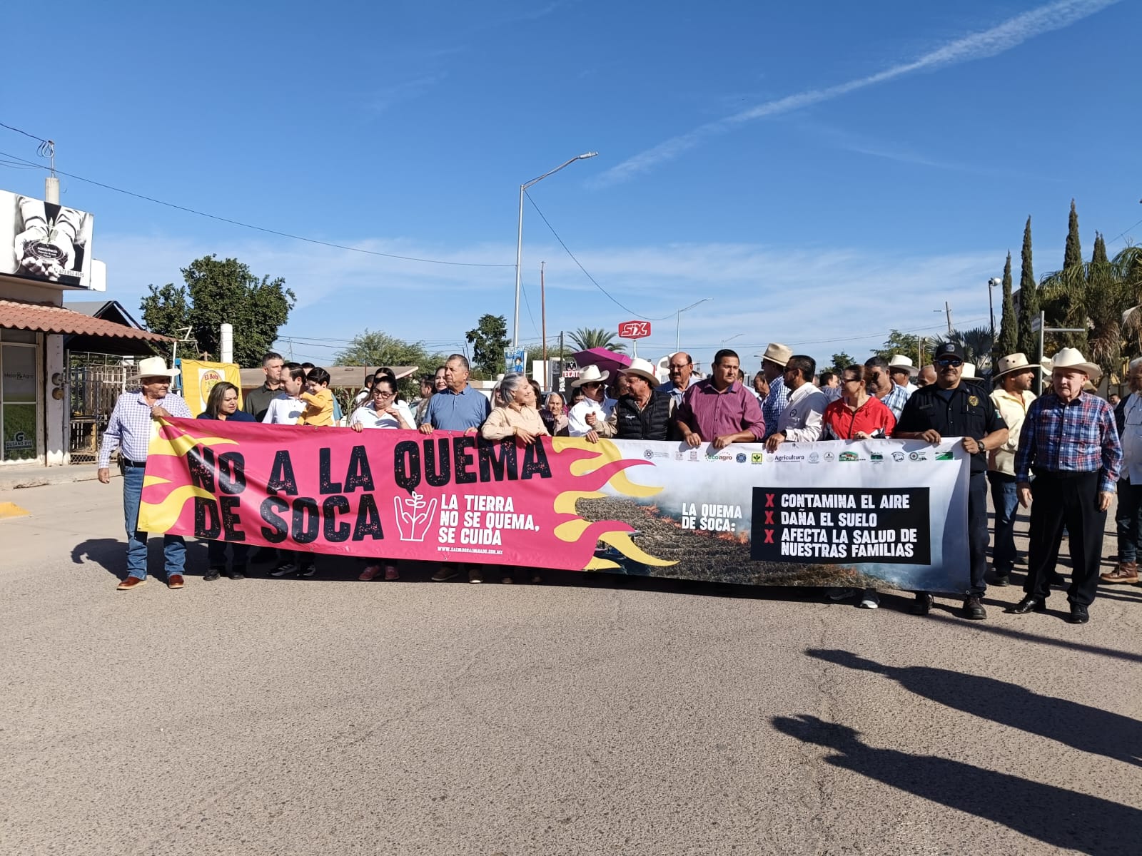 Personas caminando en la calle con un banner en contra de la quema de soca