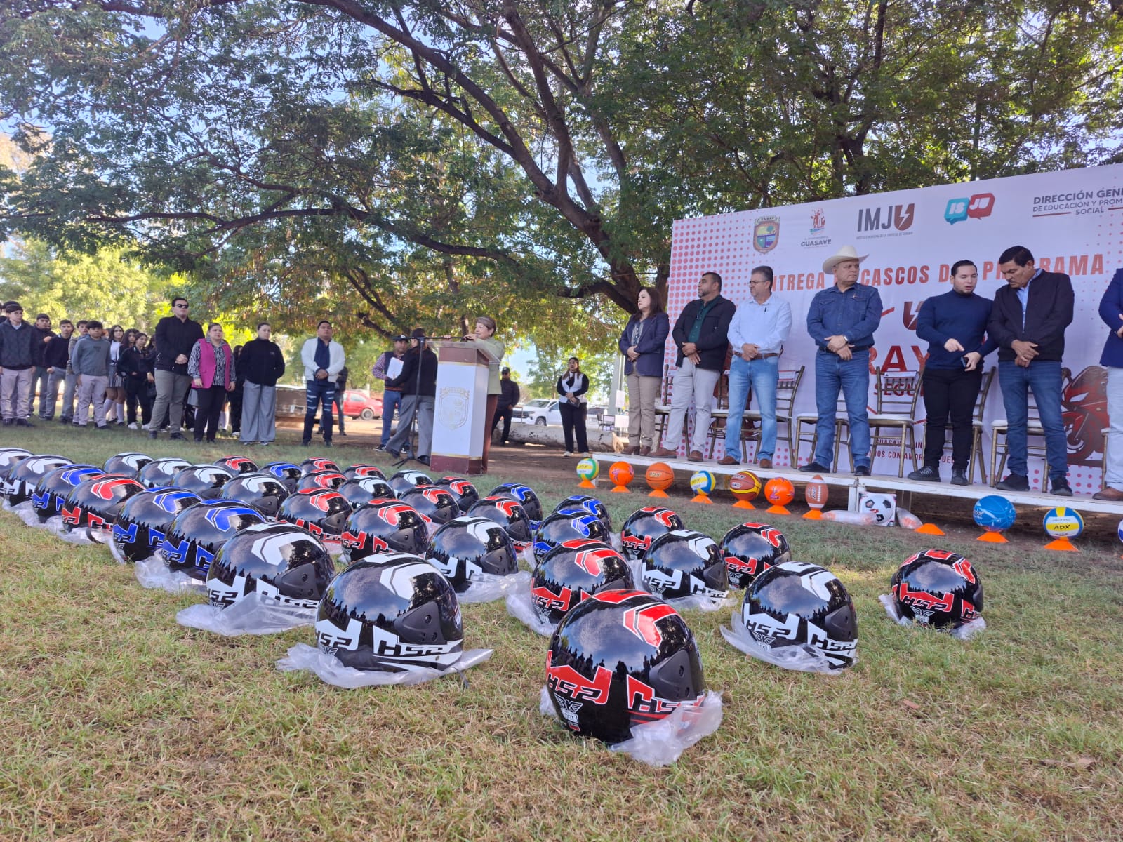 Personas arriba de una tarima en una entrega de cascos de motocicleta