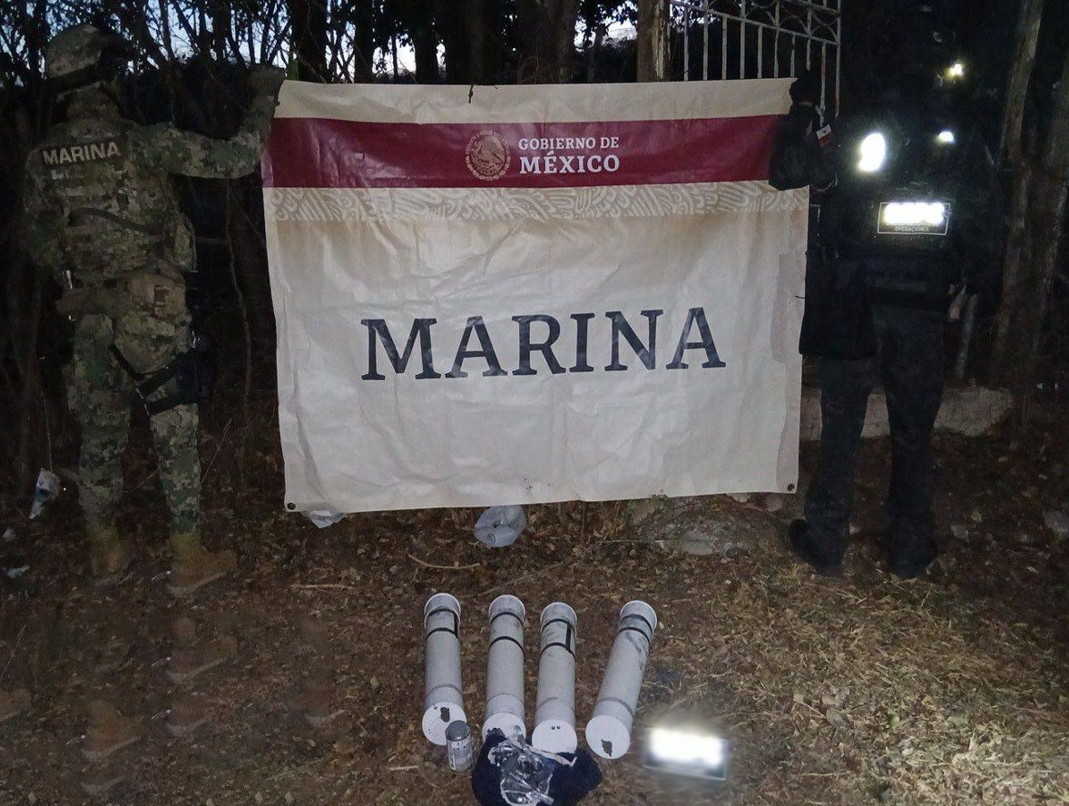 Elementos de la Marina sosteniendo una lona y en el suelo unos artefactos utilizados como explosivos