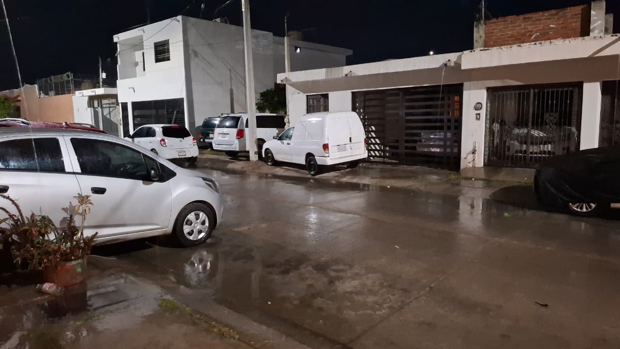 Calle mojada por lluvia, se observan carros y casas