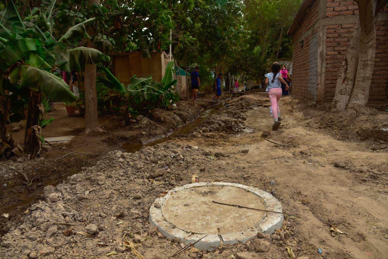 Niña corriendo en el patio de una casa y se observa una tapadera de drenaje