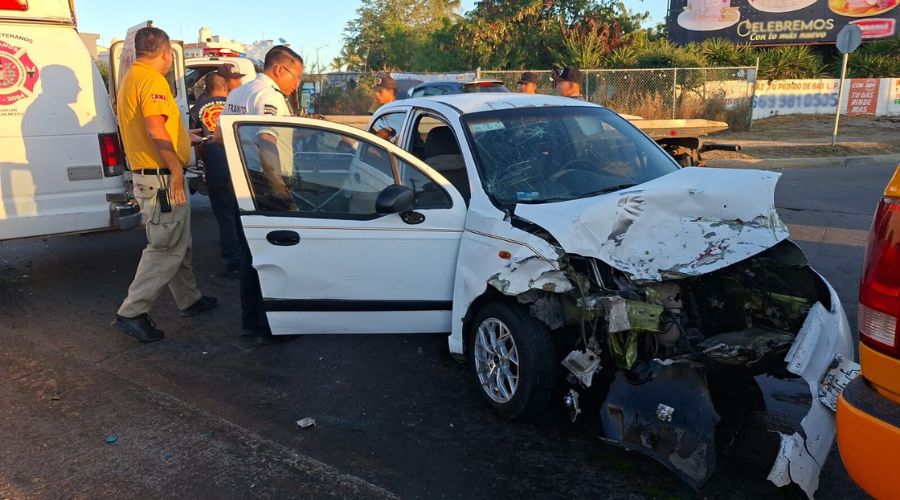 carro destrozado en un accidente vial y personal de emergencias alrededor