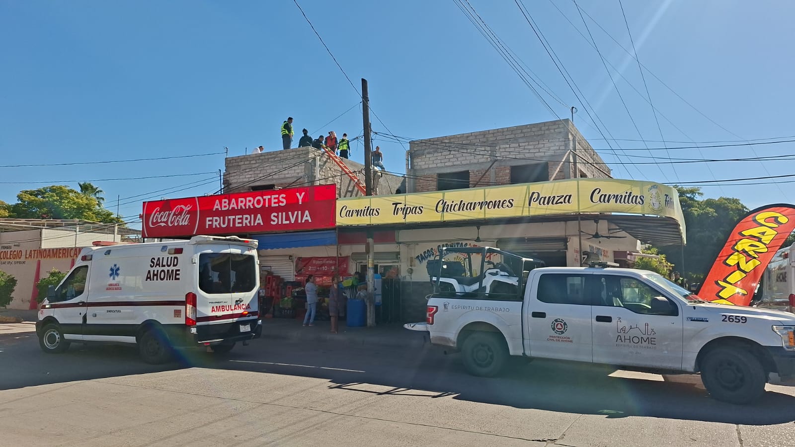 Locales de comida y abarrotes, en la parte superior bomberos y elementos de protección civil realizando maniobras de apoyo a un accidentado