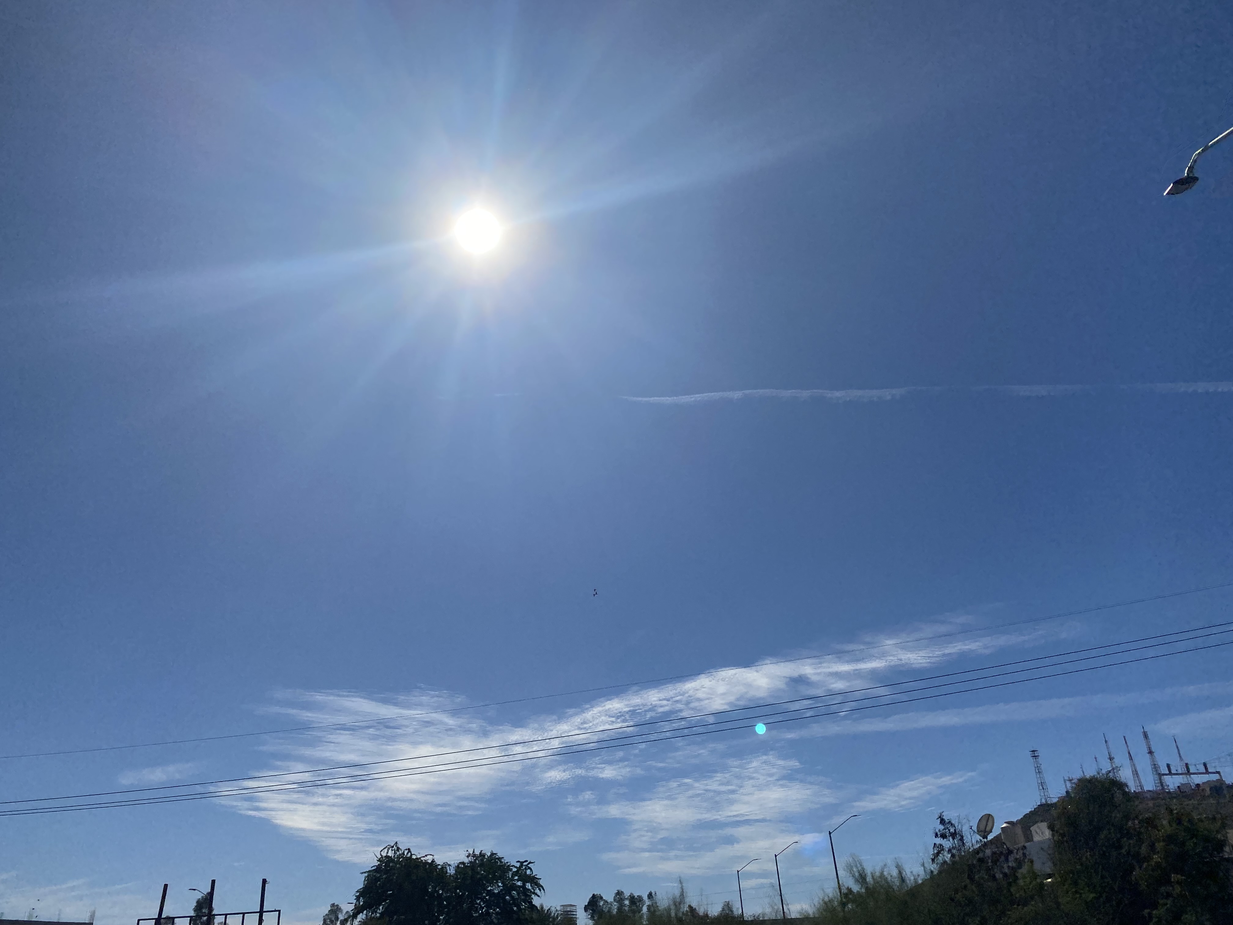 Cielo azul con sol resplandeciente en lo alto y mínimas nubes