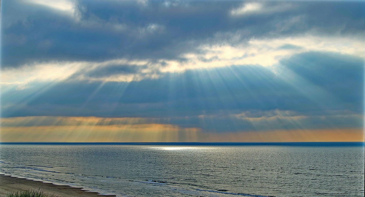 Cielo en gran parte nublado con avistamiento de la luz del sol y el mar