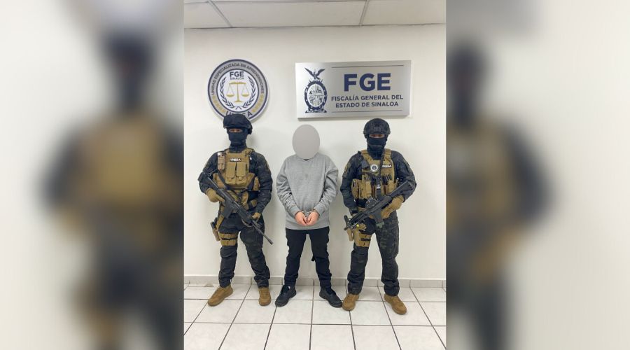 elementos policiacos a los costados y en el medio una persona detenida con las manos esposadas