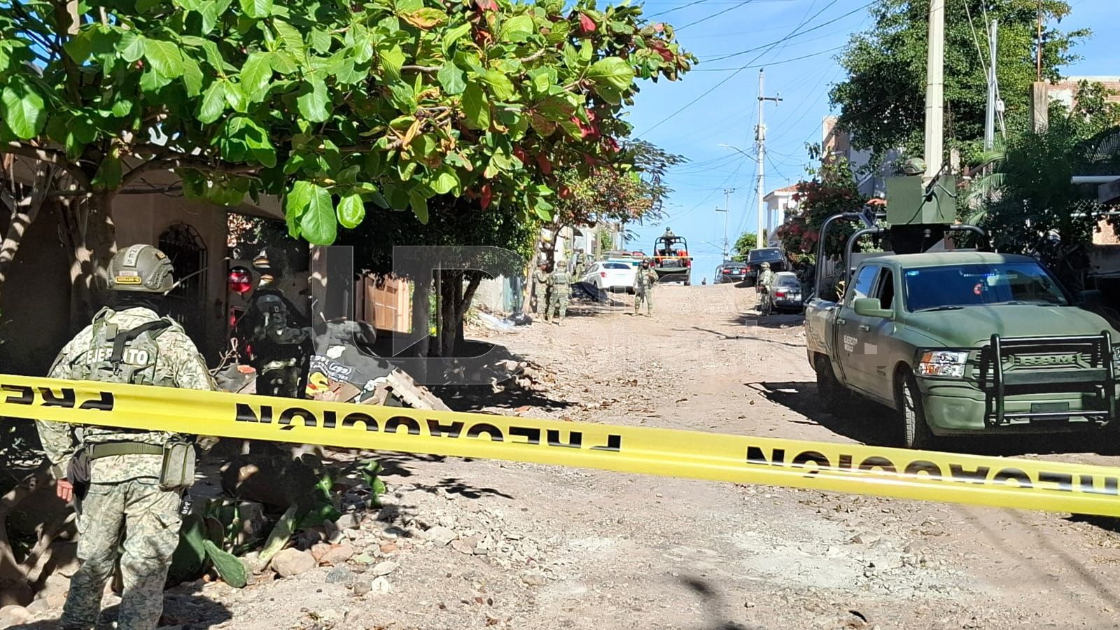 Unidad y elemento del Ejército Mexicano en un camino de terracería junto a una cinta amarilla de precaución