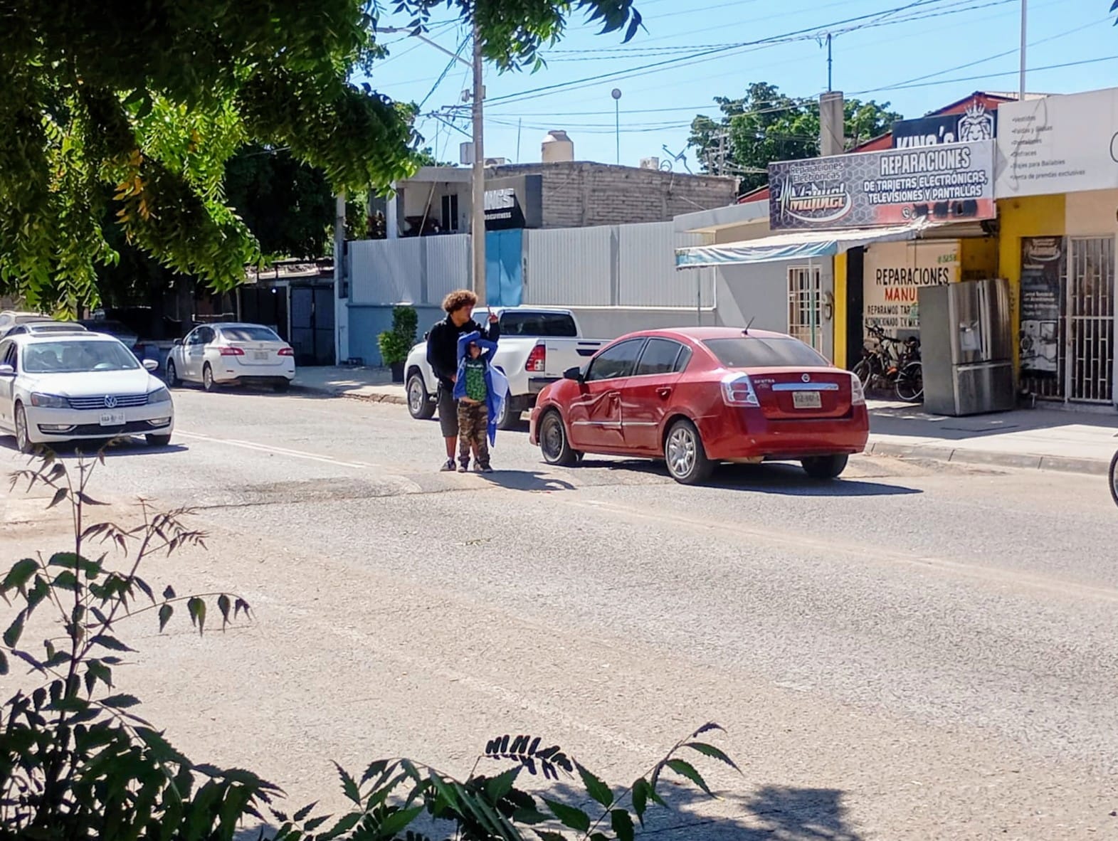 Menor acompañado de un adulto a lado de automovil