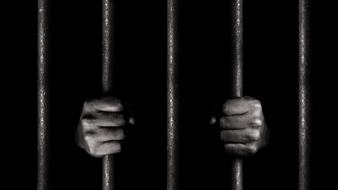 Persona sujeta rejas de celda de prisión