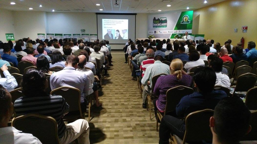 Gran cantidad de personas sentadas en un auditorio recibiendo una platica
