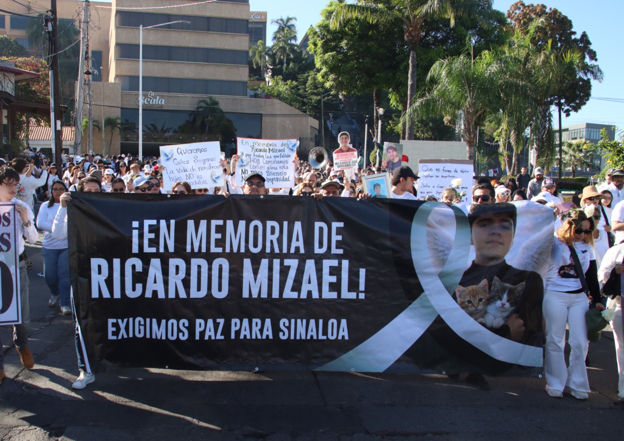 personas vestidas de blanco marchando en protesta con lona negra