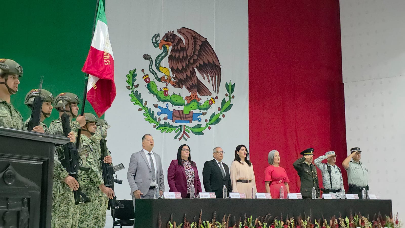 Soldados, bandera de México y personas en presencia