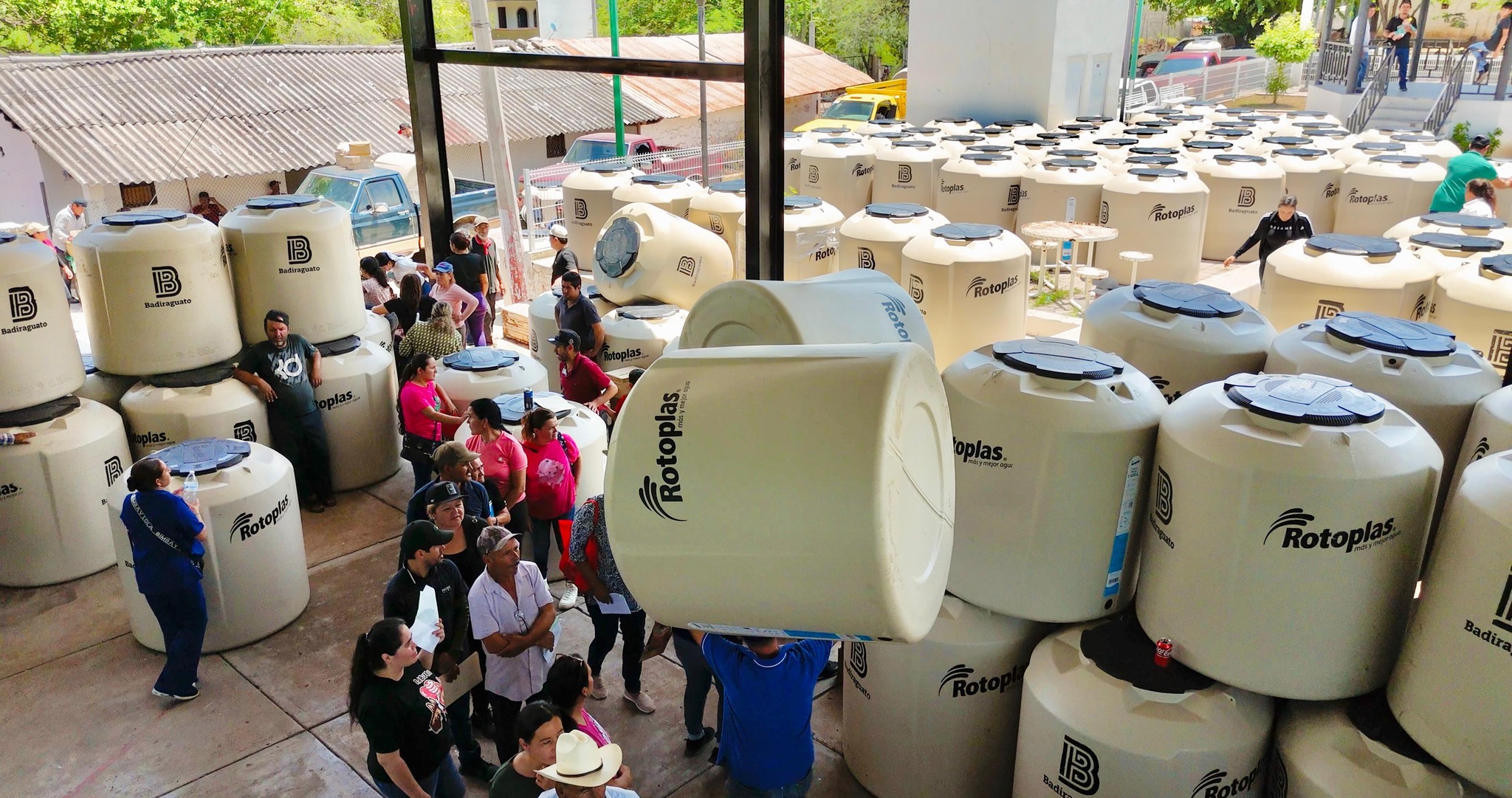 Tinacos apilados en gran cantidad y personas tomando los mismos
