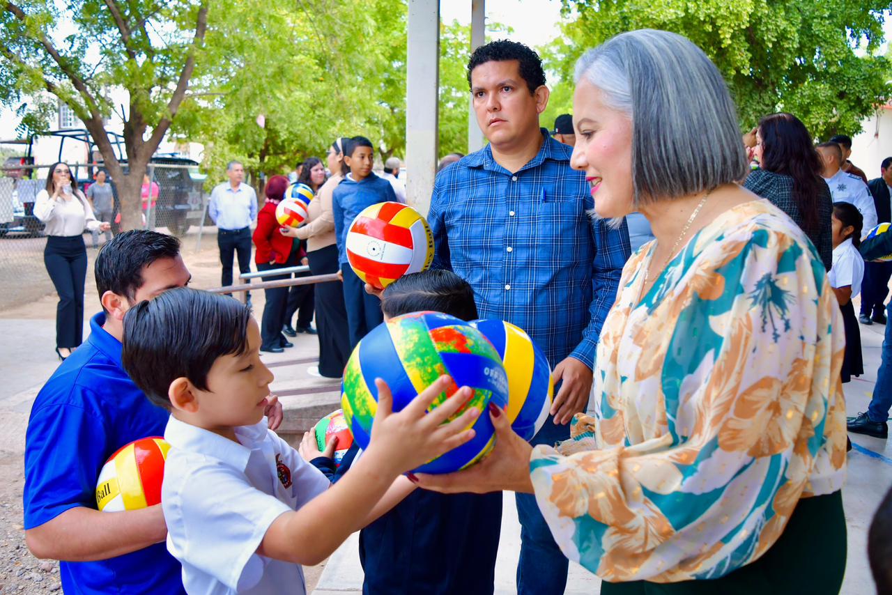 PErsonas entregando balones y equipo deportivo a niños de una primaria