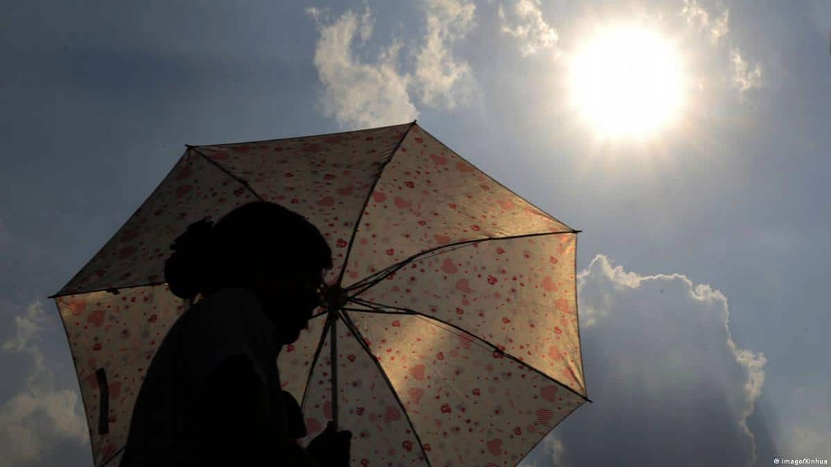 Persona con sombrilla/paraguas bajo el fuerte sol en el cielo