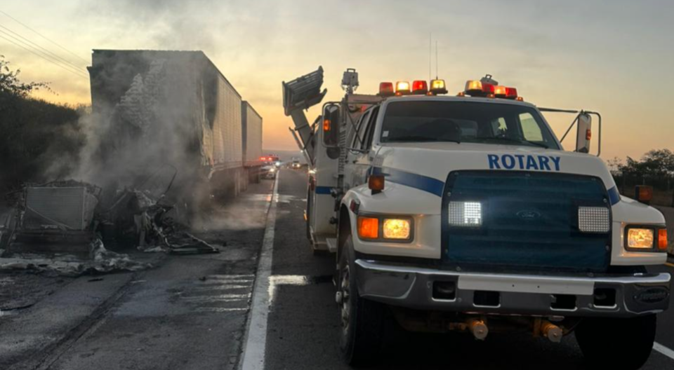 pipa de agua en carretera junto a camión incendiado