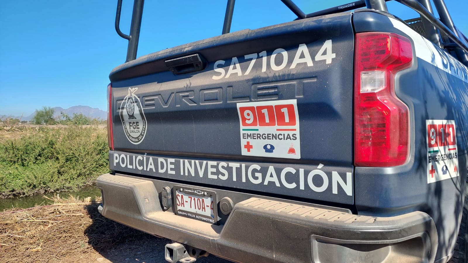 patrulla estacionada a un lado de canal de riego
