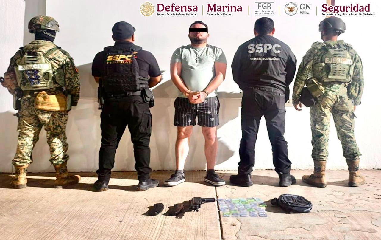 Elementos policiacos de espaldas, en el medio una persona detenida