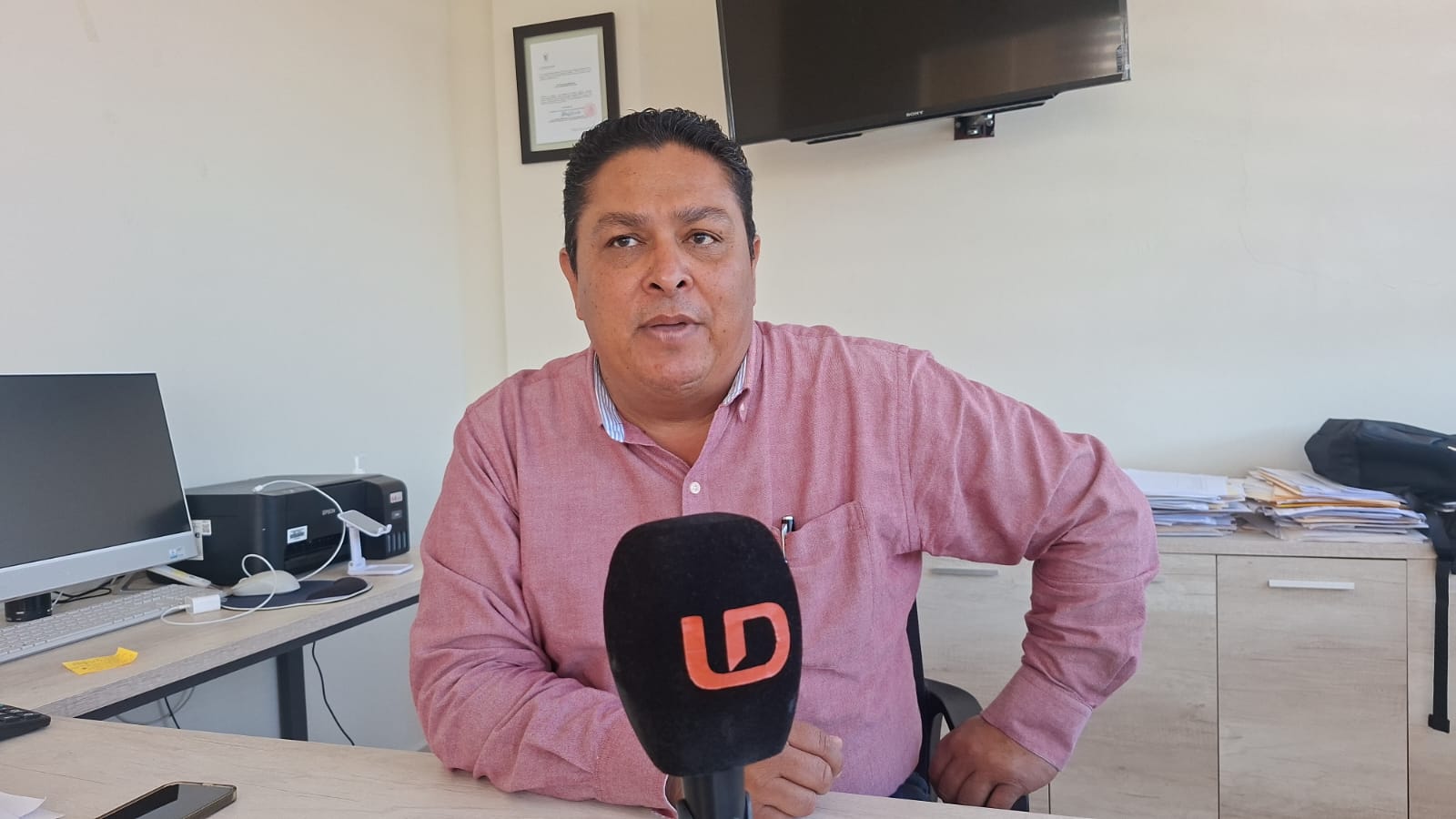 secretario del bienestar sentado en una habotación blanca hablando a micrófono de línea directa