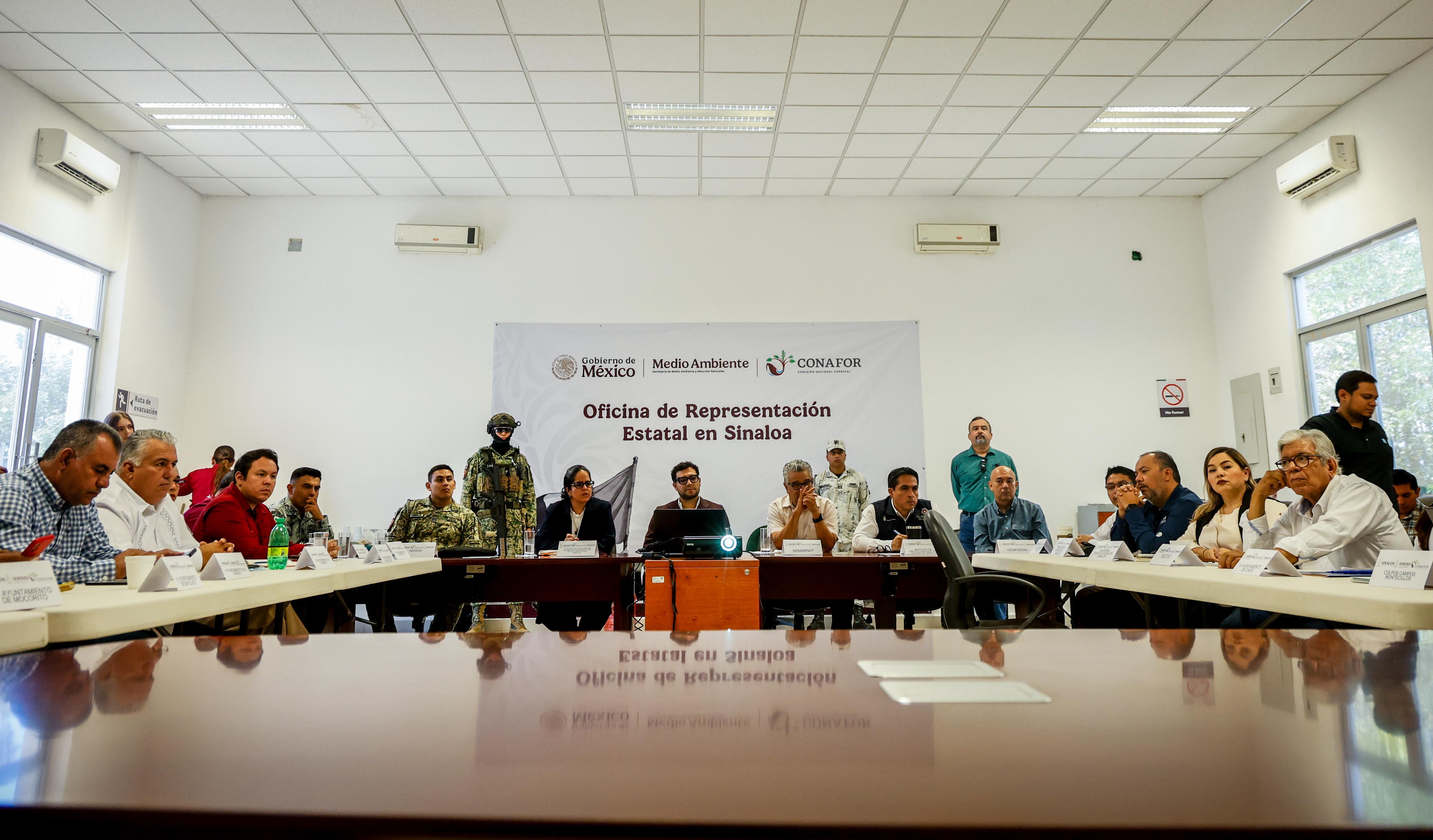 Autoridades en reunión sentados detrás de mesas grandes