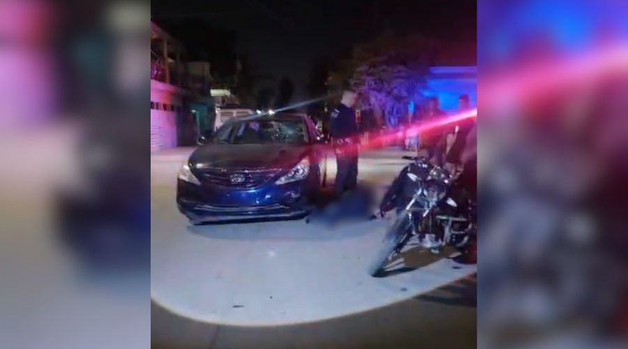 carro en una calle junto a una persona tirada y una motocicleta