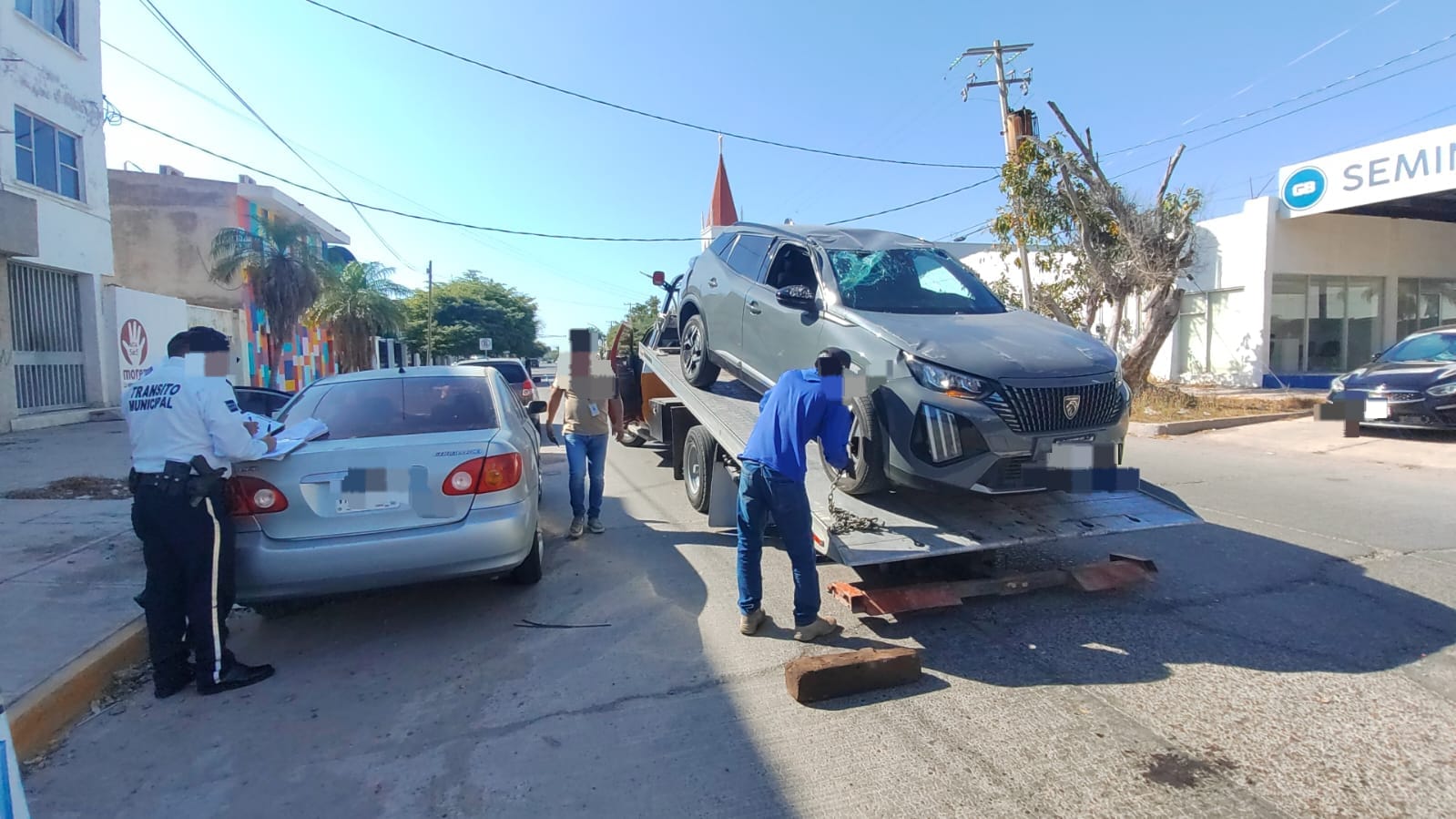Camioneta con los cristales quebrados sobre una grúa y un elemento de Tránsito