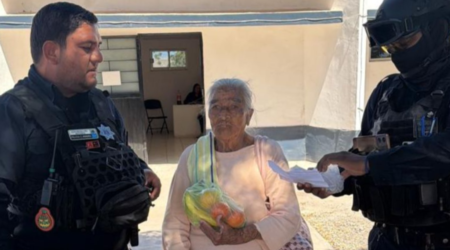 Elementos de seguridad de Juan José Ríos y en medio una mujer de la tercera edad con una bolsa que contiene alimentos