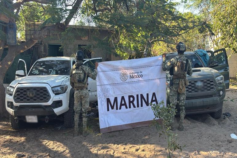 Dos elementos de seguridad junto a lona de la marina y dos camionetas