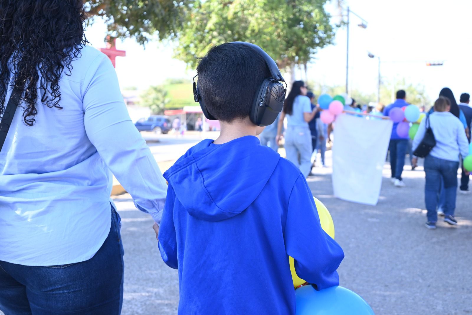 Niño con protectores para los oídos y una chamarra azul marchando