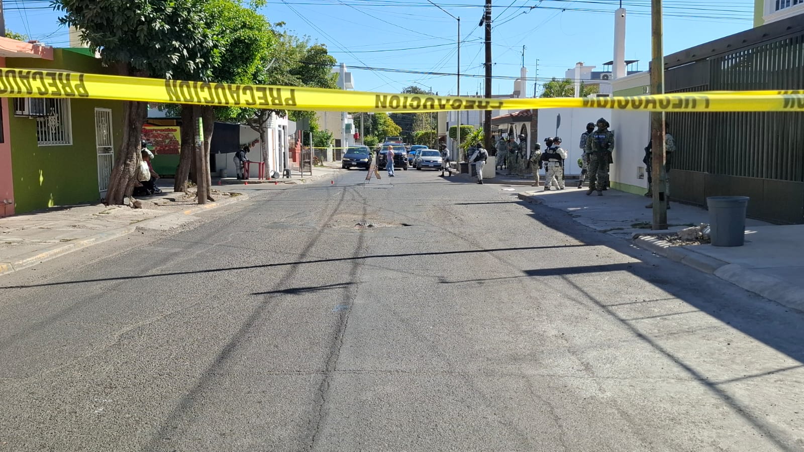 Calle acordonada con cinta amarilla y elementos del ejercito mexicano transitando la zona
