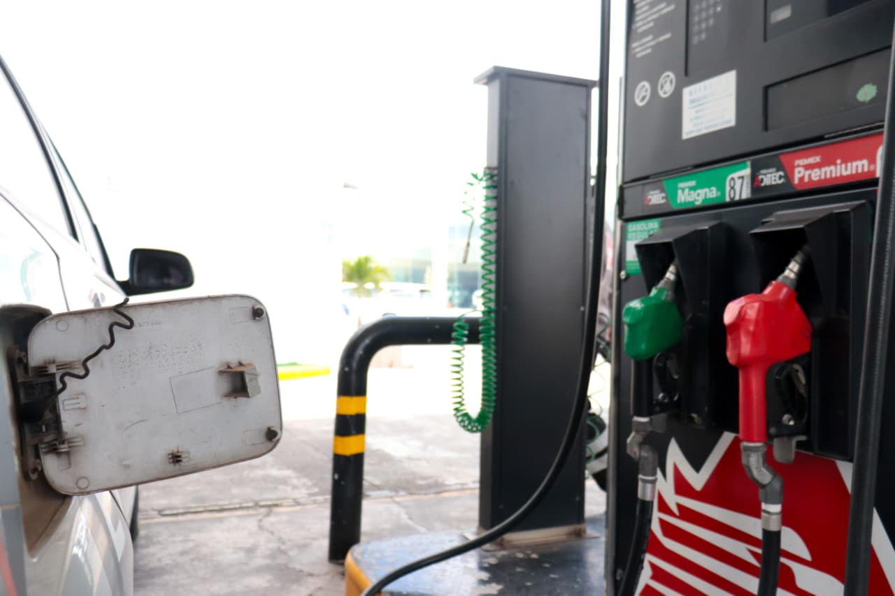 Bomba de gasolina en una estación de servicio y parte de la puerta del tanque de un carro