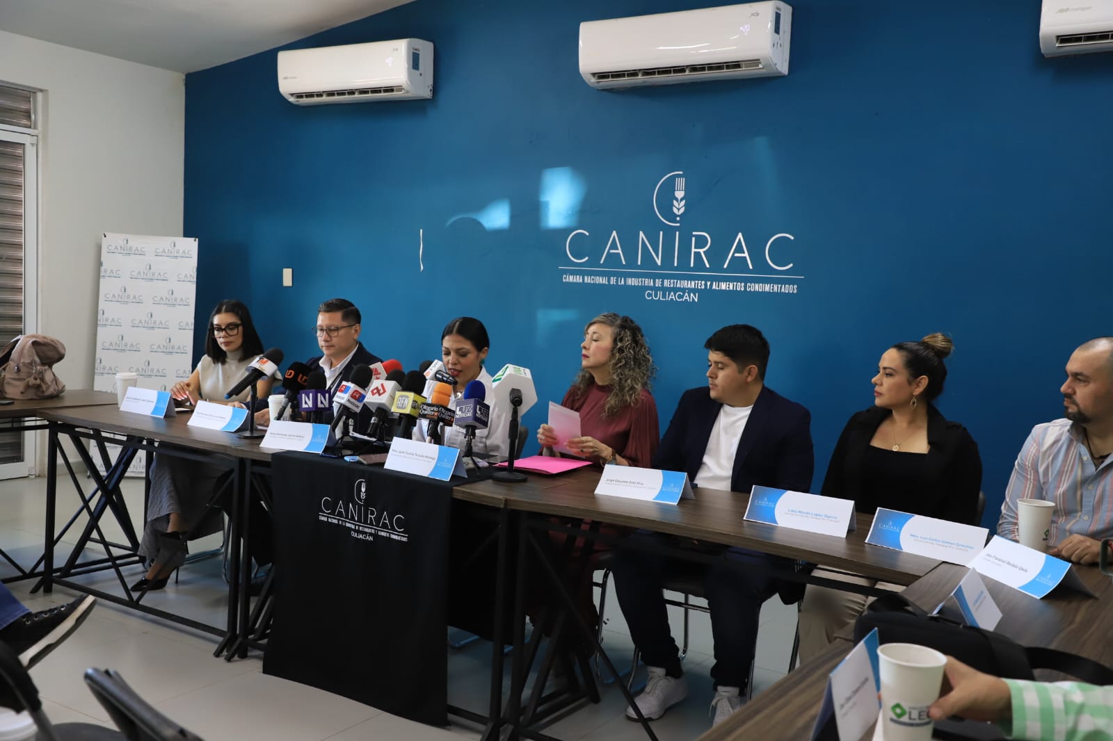 personas en una rueda de prensa con micrófonos en una mesa