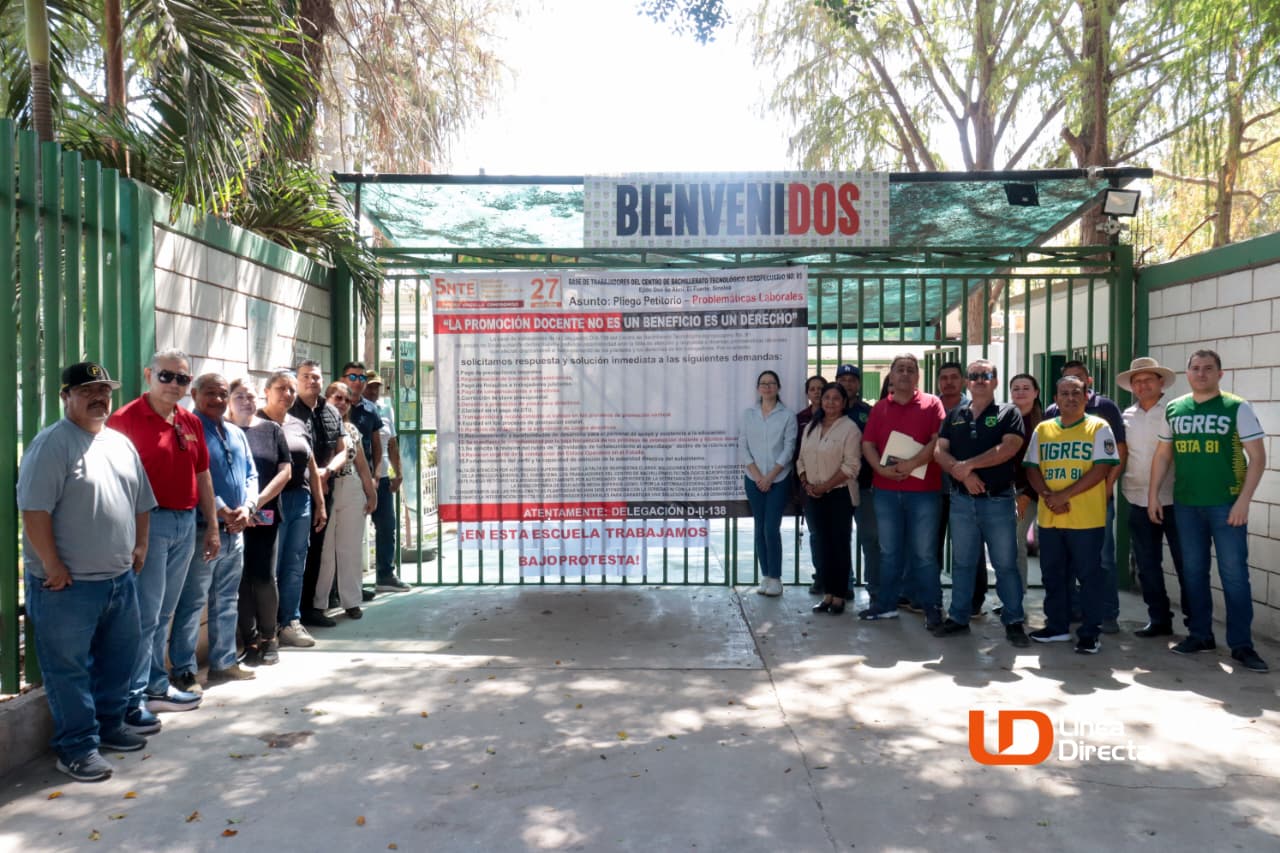 Personal del CBTA 81 junto a una lona en la puerta de la institución