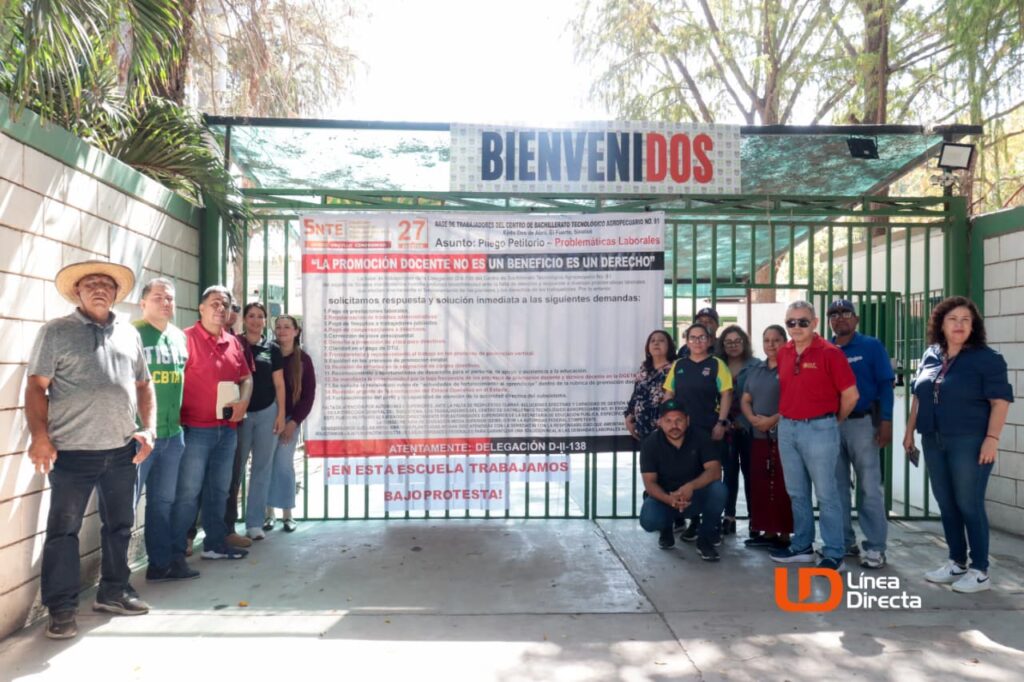 Personal del CBTA 81 en la reja con una lona de protesta