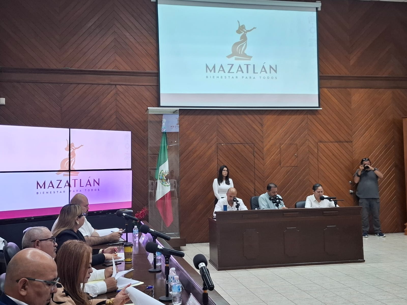 Auditorio con pantalla grande, bandera de México al fondo
