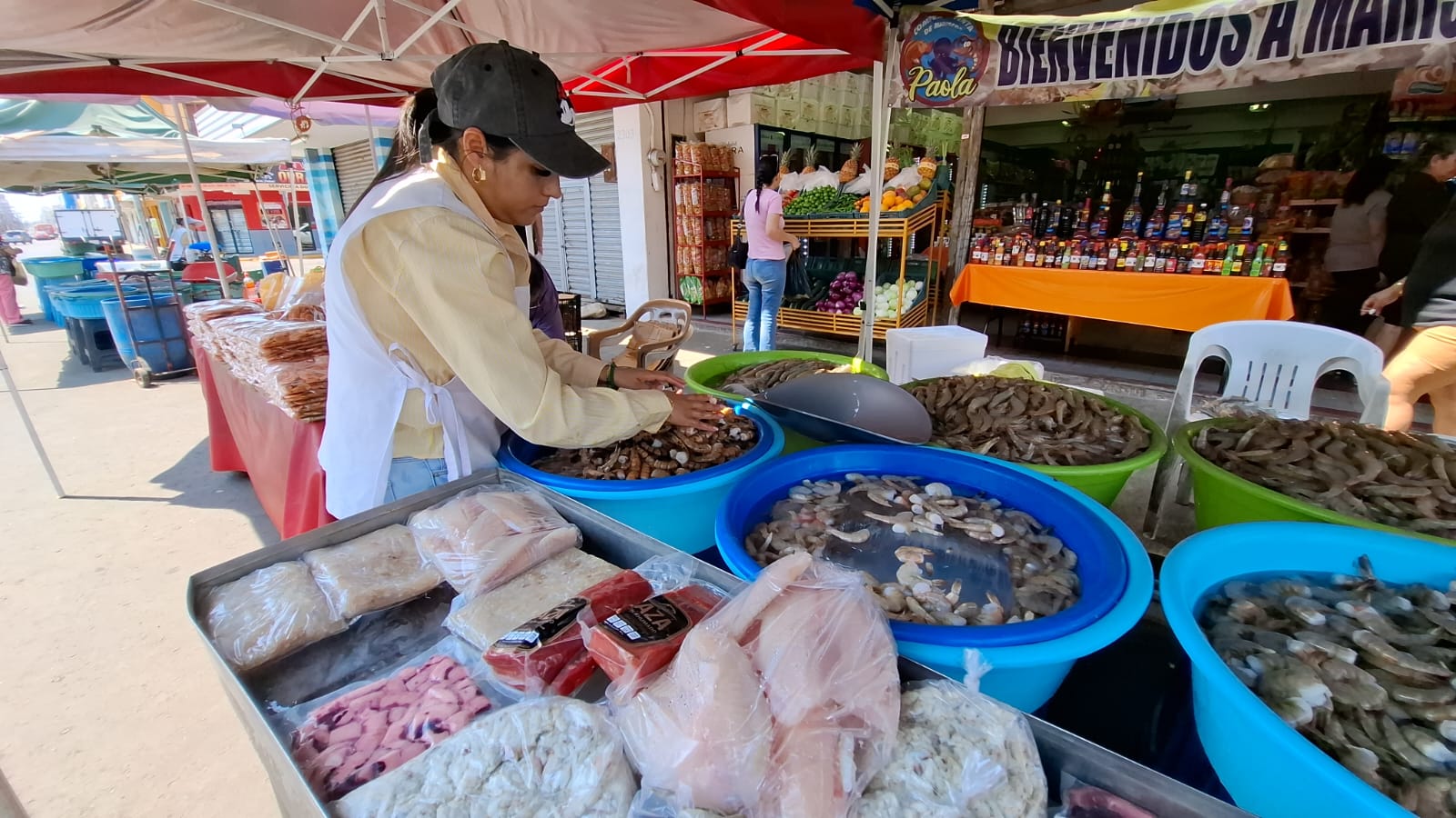 Puesto de venta de marisco y mujer realizando acomodo