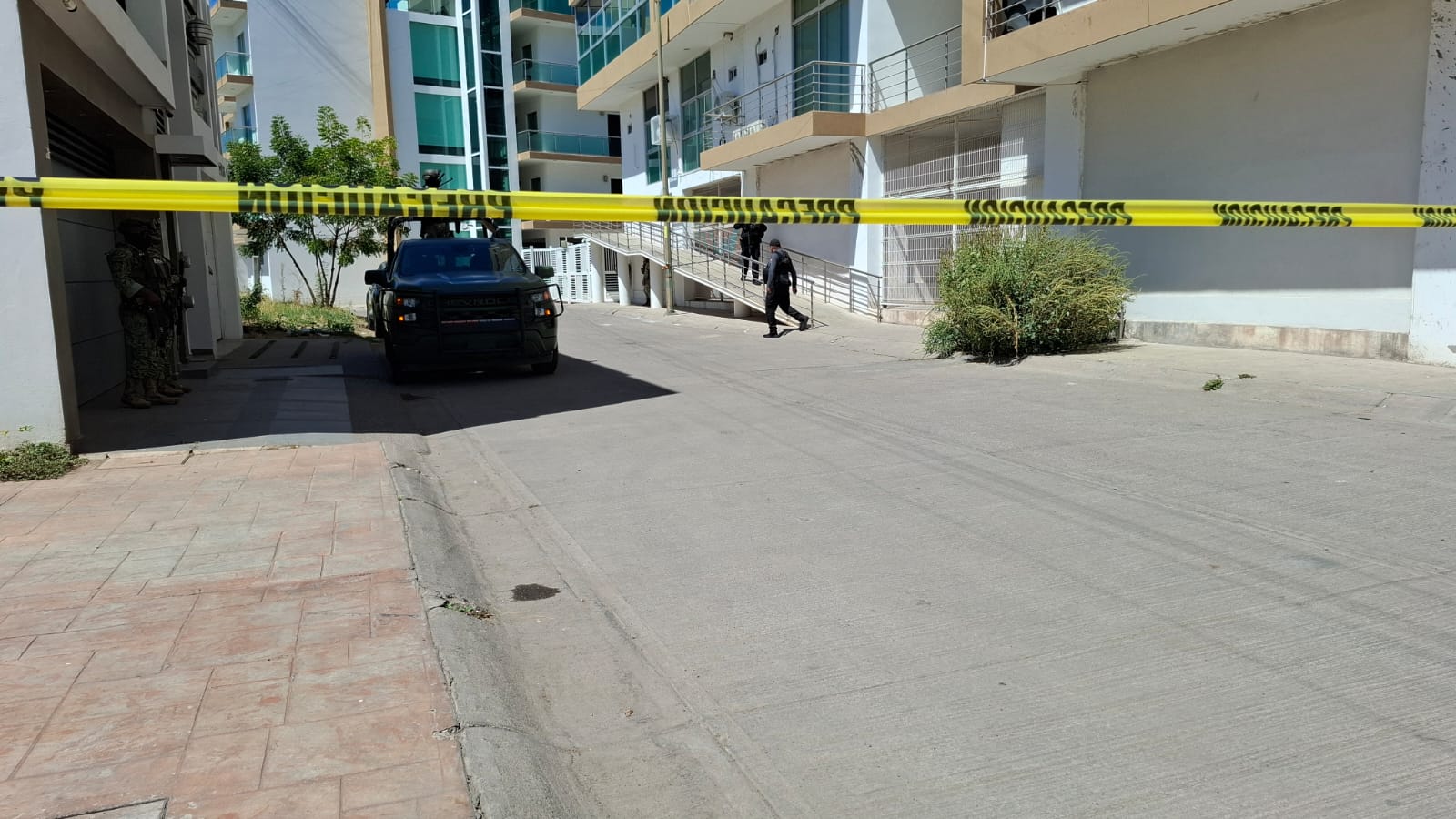 Cinta amarilla de precaución en una calle y una patrulla estacionada